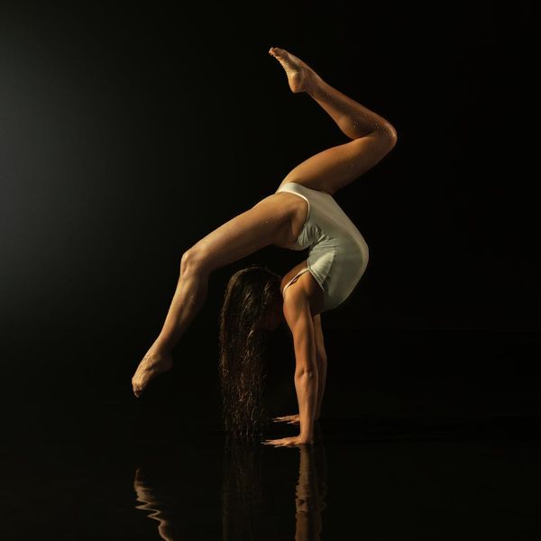 Woman performing a strength-building yoga pose against a dark background.